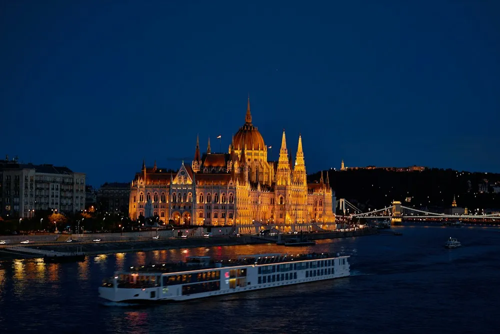 River cruise ship on the Danube in front of the Hungarian Parliament Building in Budapest at night